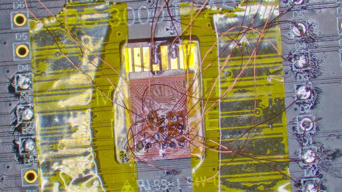 Close macro of micro-soldering and component-level cleaning work on a small circuit board under a lab magnifier.