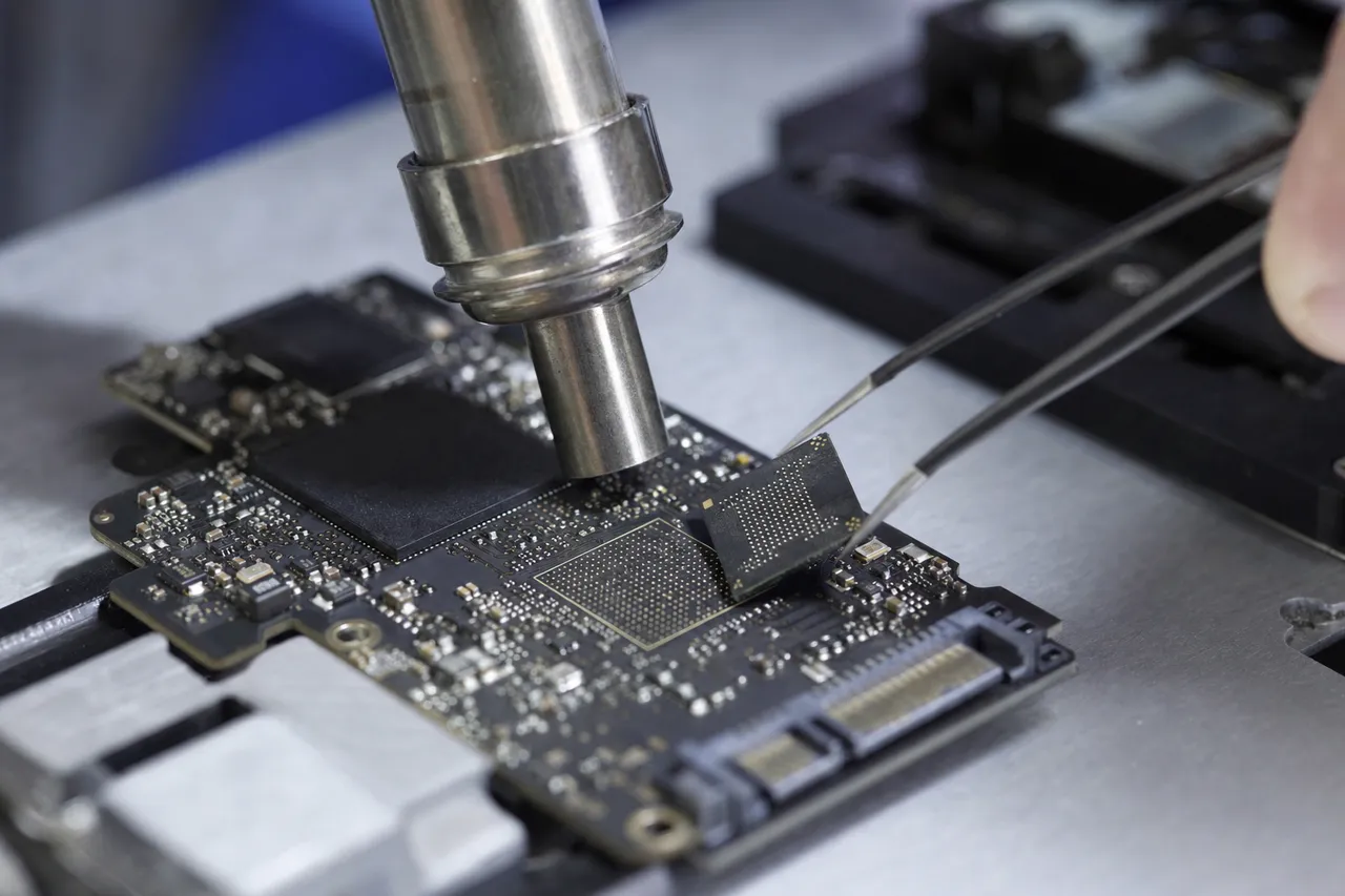 Technician performing chip-off NAND extraction on a failed solid state drive circuit board with precision tools