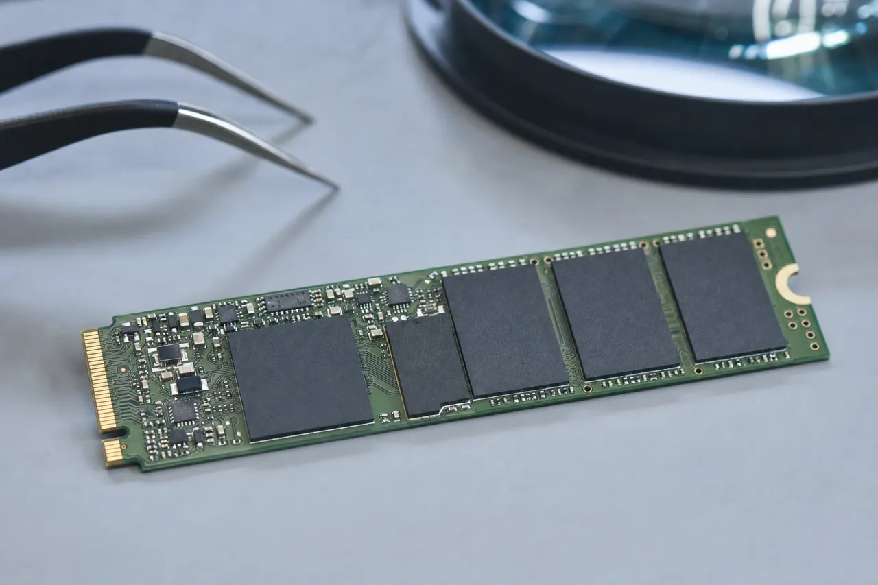 Extreme macro of an M.2 laptop SSD circuit board showing the controller chip, NAND flash packages and a DRAM cache under lab lighting.